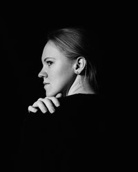 Portrait of young woman against black background