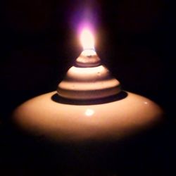 Close-up of lit candle in dark room