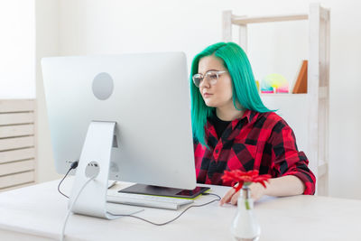 Young woman using phone while sitting on table