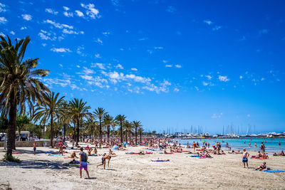 People enjoying at beach against blue sky