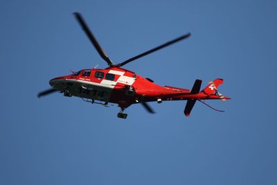 Low angle view of airplane flying against clear blue sky