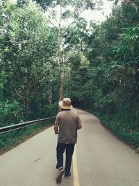 Rear view of woman walking on road in forest