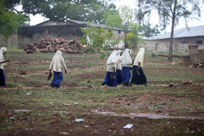 Rear view of people walking on field