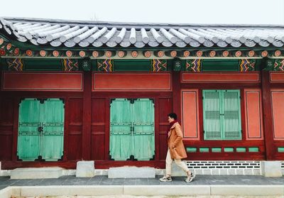 Side view of man walking on footpath in city