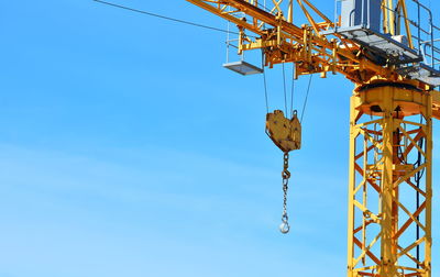 Low angle view of crane against clear blue sky