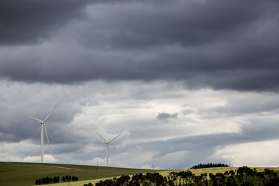 Windmills on field against sky