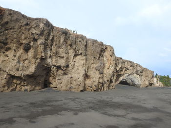 Rock formations on shore against sky