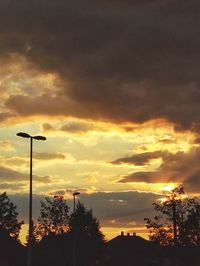 Low angle view of street lights against orange sky