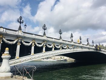 Bridge over river against cloudy sky