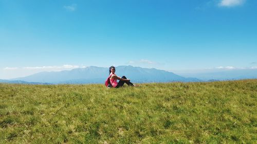 Full length of woman sitting on field against sky