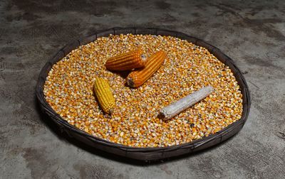 High angle view of corn and kernels in plate on floor
