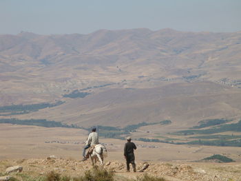 Rear view of two people walking on landscape