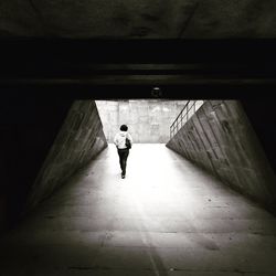 Rear view of man walking in tunnel