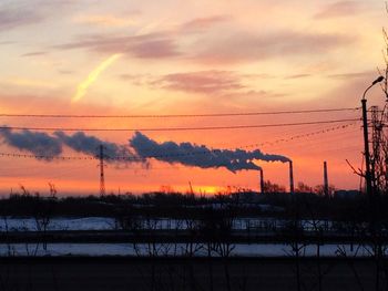 Silhouette of factory against sky during sunset