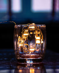 Close-up of illuminated string lights in glass on table