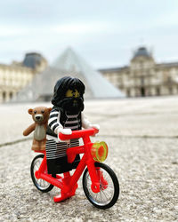 Boy riding toy car against building in city