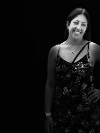 Portrait of a smiling young woman against black background