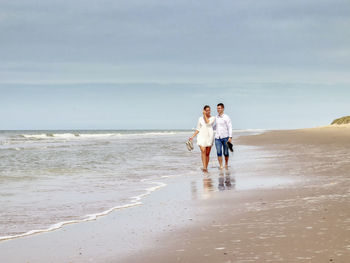 Rear view of couple walking on beach