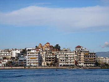 Buildings by sea against sky