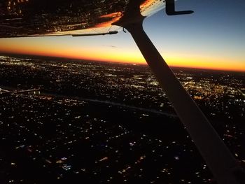 Aerial view of illuminated cityscape against sky during sunset