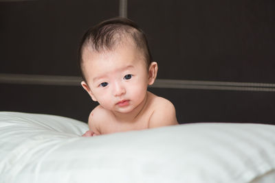 Close-up portrait of shirtless baby on bed