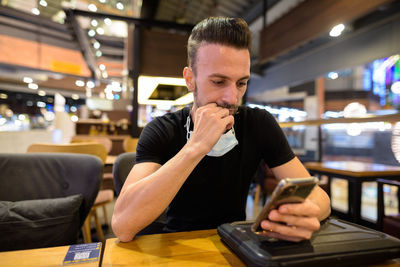 Young man using mobile phone in restaurant