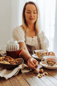 Woman eating dry fruits, figs and nuts and drinking hibiscus tea