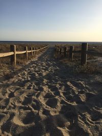 Wooden posts on beach against clear sky