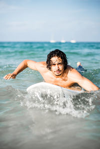 Portrait of shirtless man in sea against sky