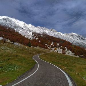 Road leading towards snowcapped mountain against sky