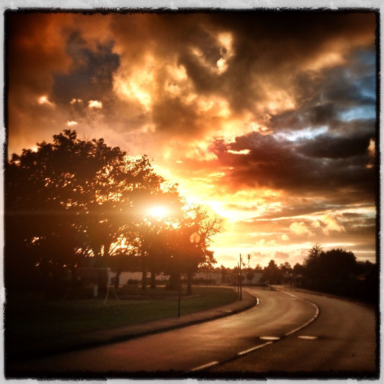 transfer print, sunset, sun, sky, auto post production filter, road, transportation, cloud - sky, tree, orange color, sunlight, the way forward, silhouette, scenics, road marking, sunbeam, tranquil scene, cloudy, nature, beauty in nature