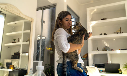 Full length of woman with cat at home