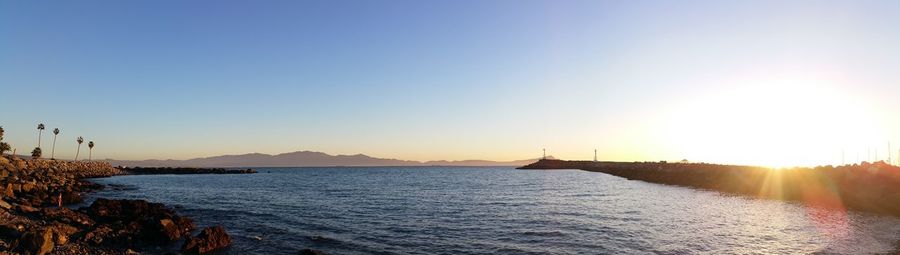 Scenic view of bay against clear sky at sunset