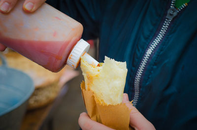 Midsection of person holding ketchup bottle and food