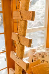 Close-up of rope tied on wood by window