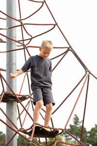 Low angle view of boy standing on slide against sky