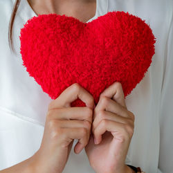 Midsection of woman holding heart shape with hands