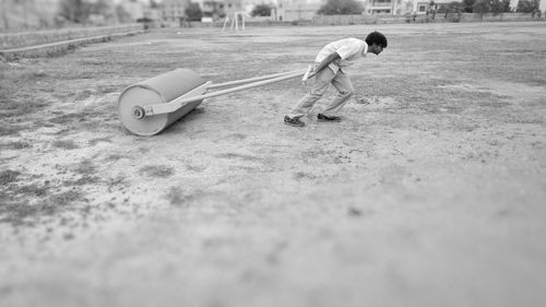 Side view of young man pulling roller on playground