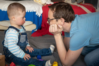 Side view of father playing with toddler son at home