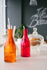 Bright colorful glass bottles with paper straws for drinks or cocktails and a bowl of cookies