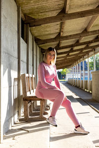 Full length of young woman sitting on wall