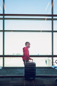 Full length of man sitting on window at airport