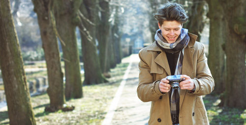 Smiling young man holding camera