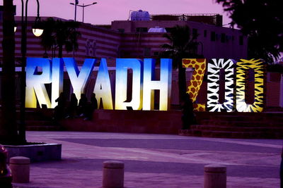 Text on illuminated street light against building at night