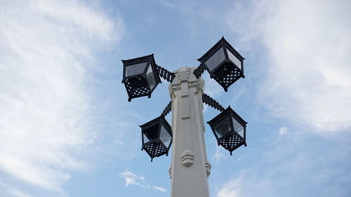 Low angle view of cross on street against sky