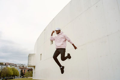 Man jumping on wall against sky