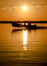 Silhouette boat in lake against sky during sunset