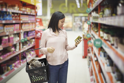 Woman looking at prices during inflation while doing shopping in supermarket