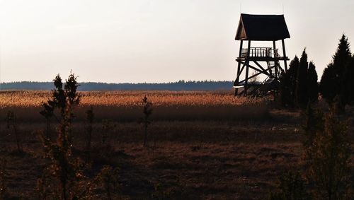 Lookout tower on field against clear sky during sunny day