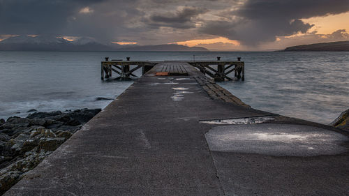 Pier over sea against sky during sunset